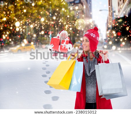 Blonde in winter clothes holding shopping bags against santa delivering gifts in city