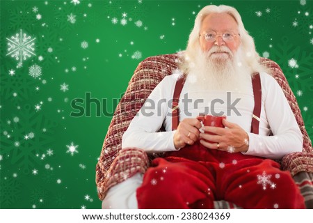 Father christmas sitting on the armchair holding mug against red background