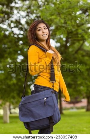 Portrait of smiling female college student with bag in the park