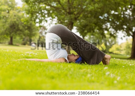 Brown hair doing yoga on grass in the park