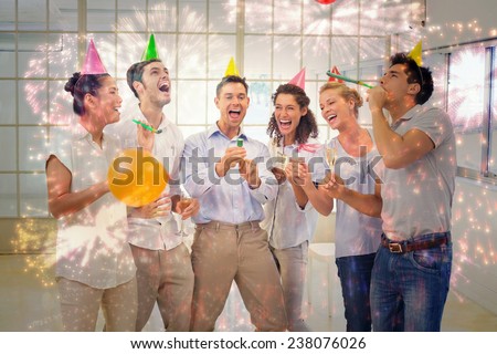 Casual business team celebrating with champagne and party poppers against colourful fireworks exploding on black background