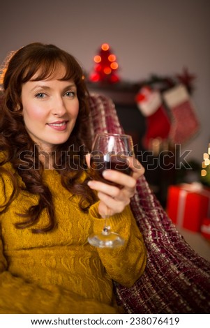 Woman sitting on a couch while holding a glass of red wine at christmas at home in the living room