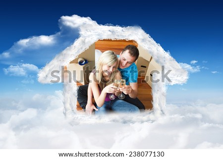 Cute lovers celebrating new house with champagne against bright blue sky with clouds