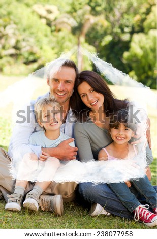 Family sitting in the park against house outline in clouds