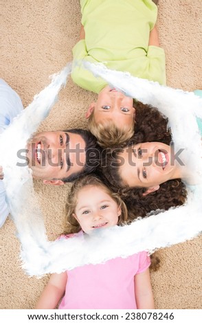 Smiling family lying on the rug in a circle against house outline in clouds