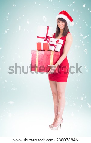 Festive brunette holding pile of gifts against blue vignette