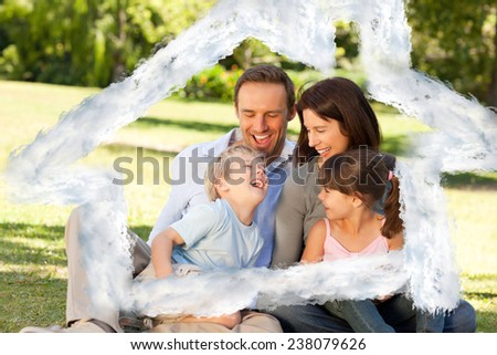 Family looking at their photo album in the park against house outline in clouds