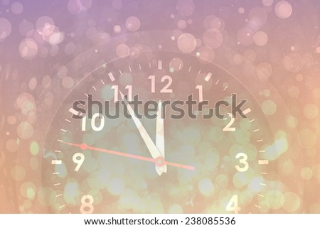 Clock counting down to midnight against pink abstract light spot design