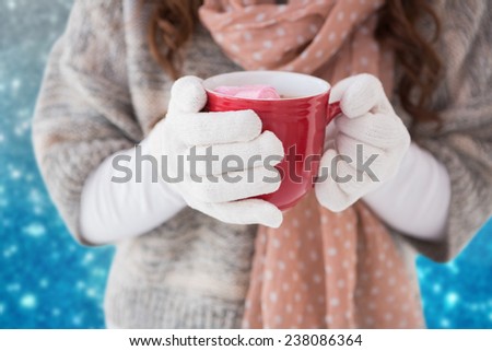 Woman in winter clothes holding a mug against blurred lights