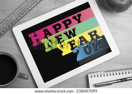 Colourful happy new year against overhead of tablet on desk
