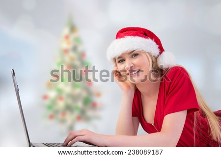 Festive blonde using a laptop against blurry christmas tree in room