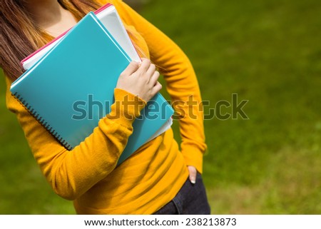 Mid section of female college student with books in the park