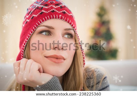 Woman in winter hat thinking with head on hand against snow falling