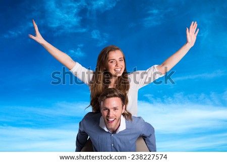 Smiling young man carrying woman against blue sky