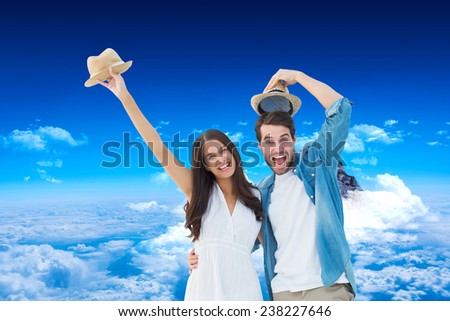 Happy hipster couple smiling at camera and cheering against mountain peak through clouds