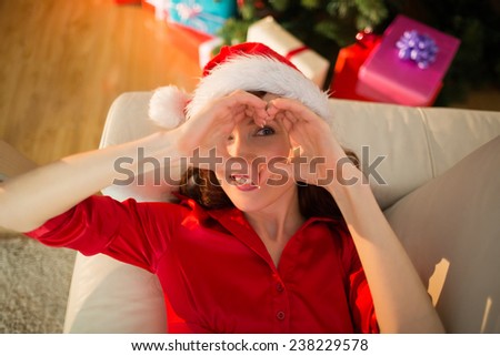 Smiling redhead doing heart sign at christmas at home in the living room