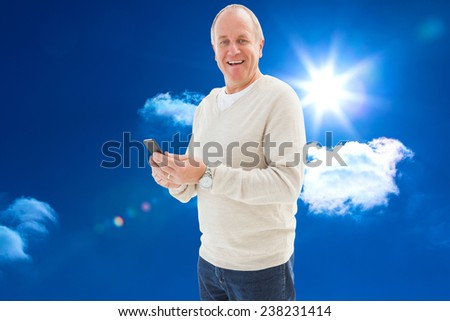 Happy mature man sending a text against bright blue sky with clouds