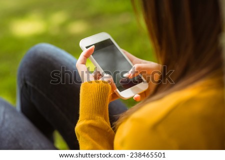 Side view of young woman text messaging in the park