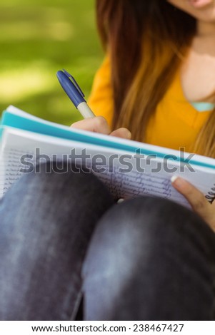 Close up mid section of female college student doing homework in the park