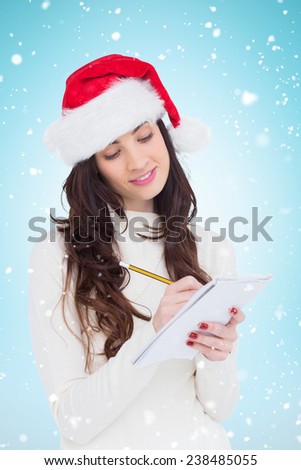 Festive brunette writing her christmas list against blue background with vignette