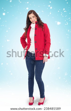 Beauty brunette posing in red coat and heels against blue background with vignette