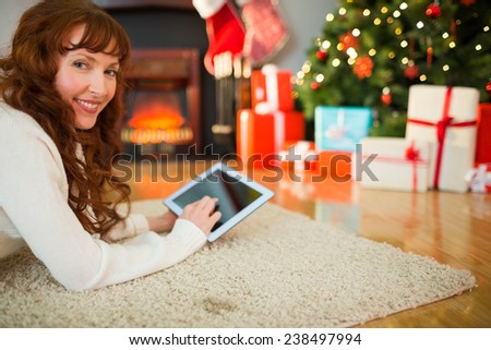 Redhead woman lying on floor using tablet at christmas at home in the living room