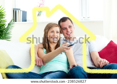 Charismatic man embracing his girlfriend while watching tv against house outline