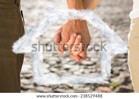 Happy senior couple holding hands against house outline in clouds