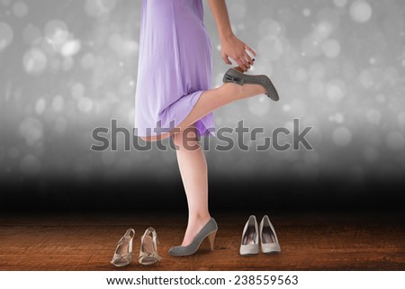 Mid section of woman trying heels against shimmering light design over boards