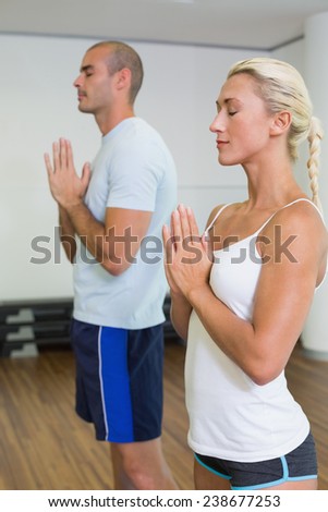Sporty young couple with joined hands and eyes closed at fitness studio