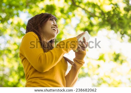 Low angle view of beautiful young woman text messaging in the park