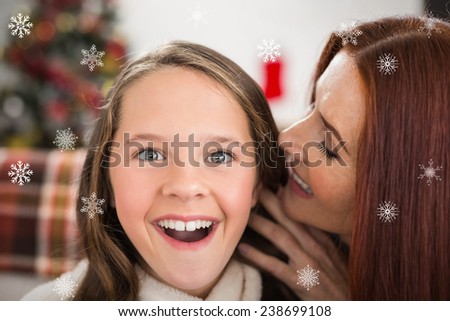 Mother telling her daughter a christmas secret against snowflakes