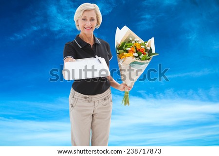 Happy flower delivery woman looking for signature against blue sky