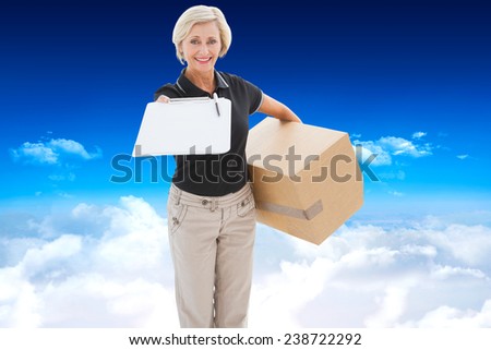 Happy delivery woman looking for signature against bright blue sky over clouds