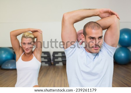 Portrait of young couple stretching hands behind back in yoga class