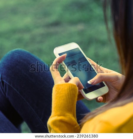 Side view of young woman text messaging in the park