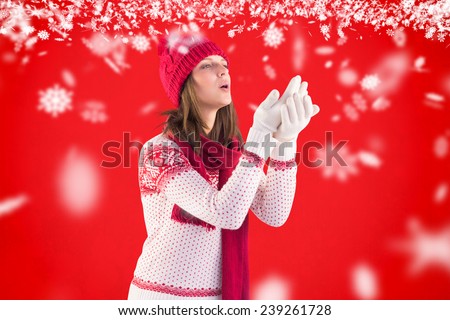 Woman in warm clothing blowing over hands against red background