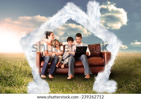 Happy family using the laptop in a field against house outline in clouds