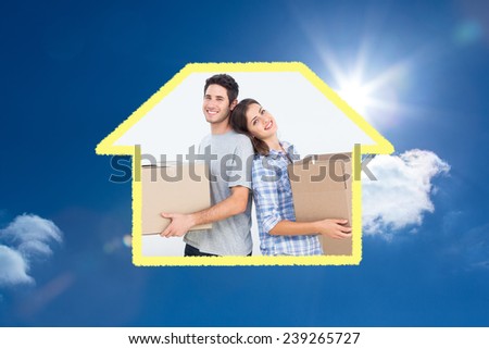 Wife and husband carrying boxes in their new house against bright blue sky with clouds