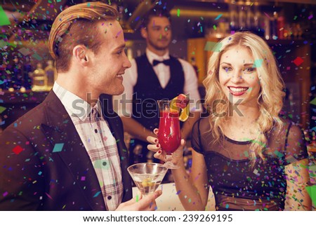 Attractive friends drinking cocktails together against flying colours