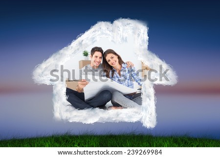man and woman holding house plans against green grass under blue and purple sky
