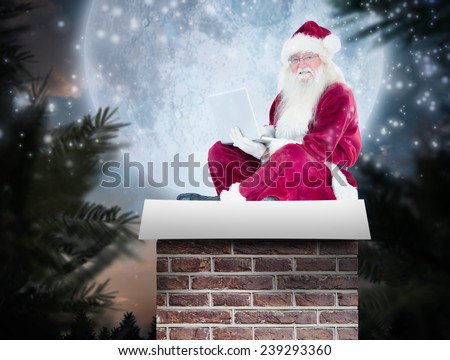Santa sits and uses a laptop against full moon over forest