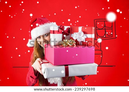 Festive redhead holding pile of gifts against red background