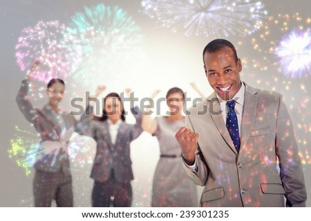 Successful business team with a man in the foreground against colourful fireworks exploding on black background
