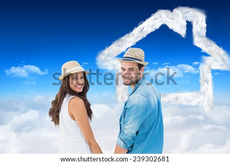 Happy hipster couple holding hands and smiling at camera against bright blue sky over clouds