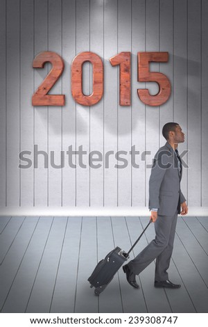 Young businessman pulling his suitcase against grey room