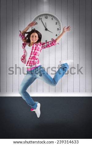 Casual brunette jumping and smiling against grey room