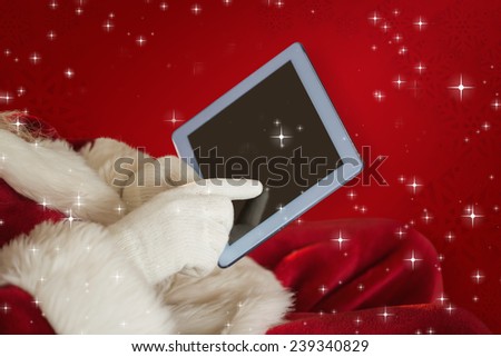 Santa using tablet on the armchair against red snowflake background