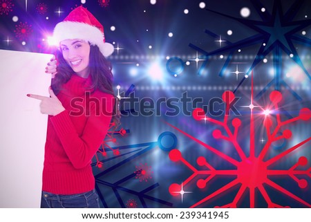 Smiling brunette in santa hat pointing white poster against digitally generated nightlife light design