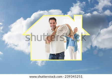 Smiling couple carrying rolled rug after moving in house against cloudy sky